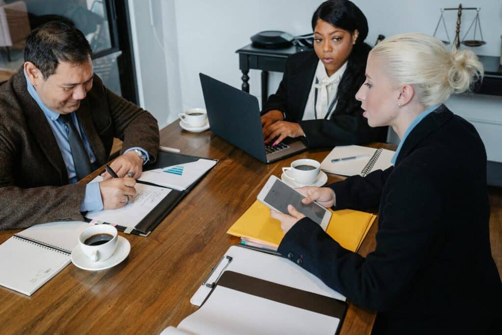 A diverse group of business professionals collaborating in a meeting with laptops and documents.