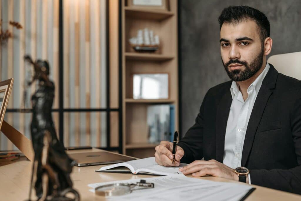 Confident bearded man in an office working on legal documents with a laptop.
